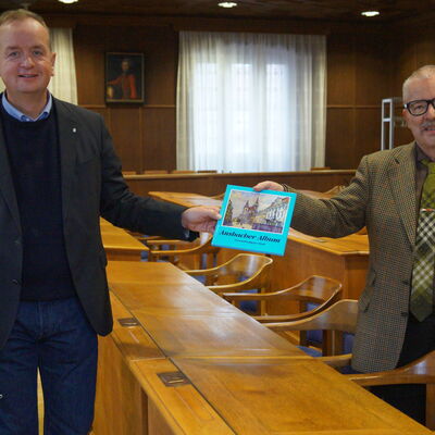 Stadtheimatpfleger Hartmut Schötz (rechts) überreicht Oberbürgermeister Thomas Deffner das neue Ansbacher Album