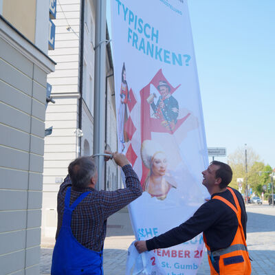 Bild vergrößern: Mitarbeiter des Betriebsamts kümmern sich um die Festbeflaggung in Ansbach.